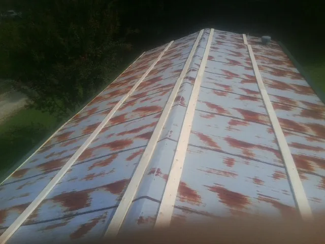 Rusted metal roof panels with new wood purlins before replacement — Storm Damage Roof Repair in North Freedom by Roofing Brothers