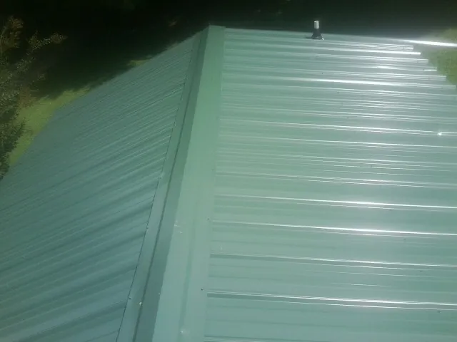 New green metal panels meeting at the ridge of a roof — Flat Roof Repair work by our crew in North Freedom