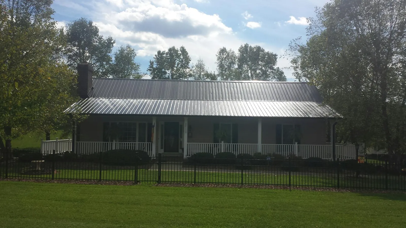 Gray metal roof on a brick ranch with a full width front porch — Gutter Guard Installation work by our crew in North Freedom