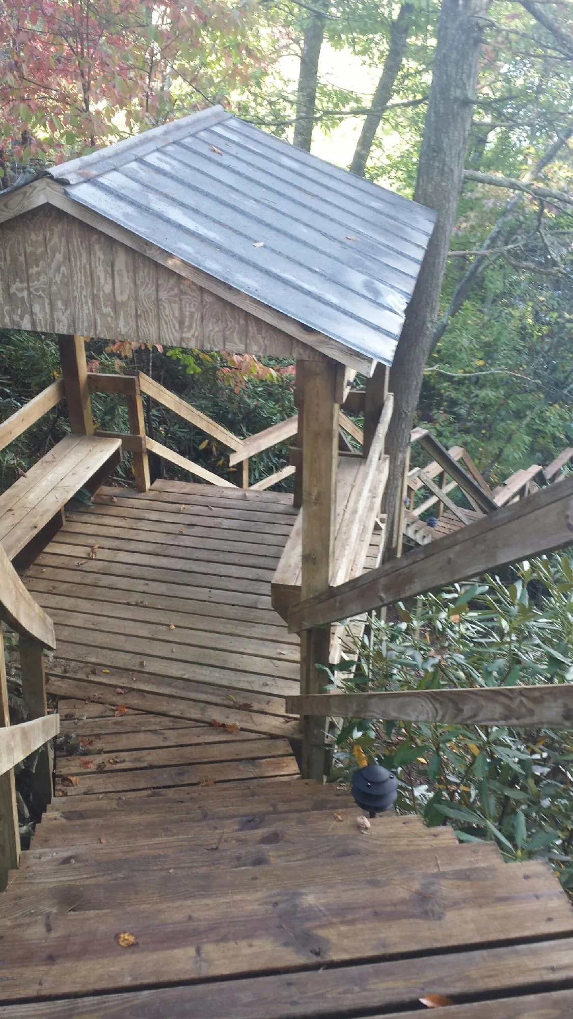 Metal roofed shelter over wooden steps on a wooded walkway — Skylight Repair & Installation work by our crew in North Freedom