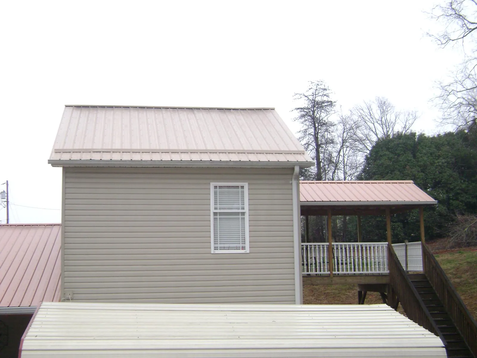 Tan metal roofs on a two story addition and attached porch, from a Roof Replacement job in North Freedom