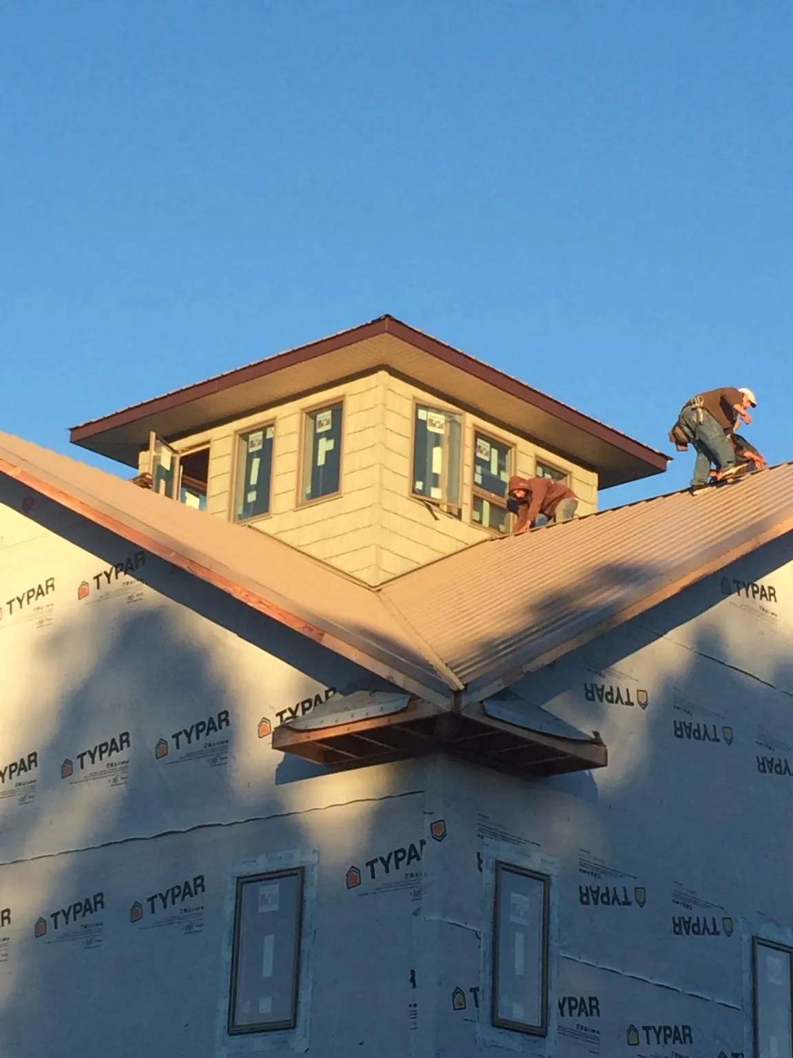 Roofers working around a rooftop cupola on a new metal roof at sunset — Roof Waterproofing in North Freedom by Roofing Brothers